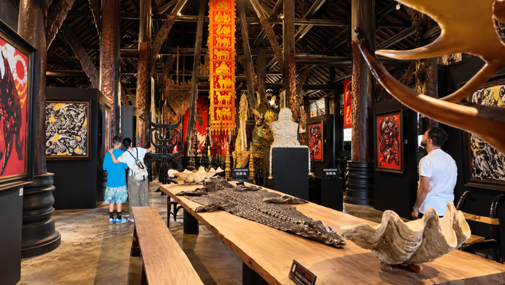 Interior of the Black House Museum (Baan Dam) in Chiang Rai, Thailand, featuring dark wooden architecture, traditional artwork, animal hides, and unusual sculptures.