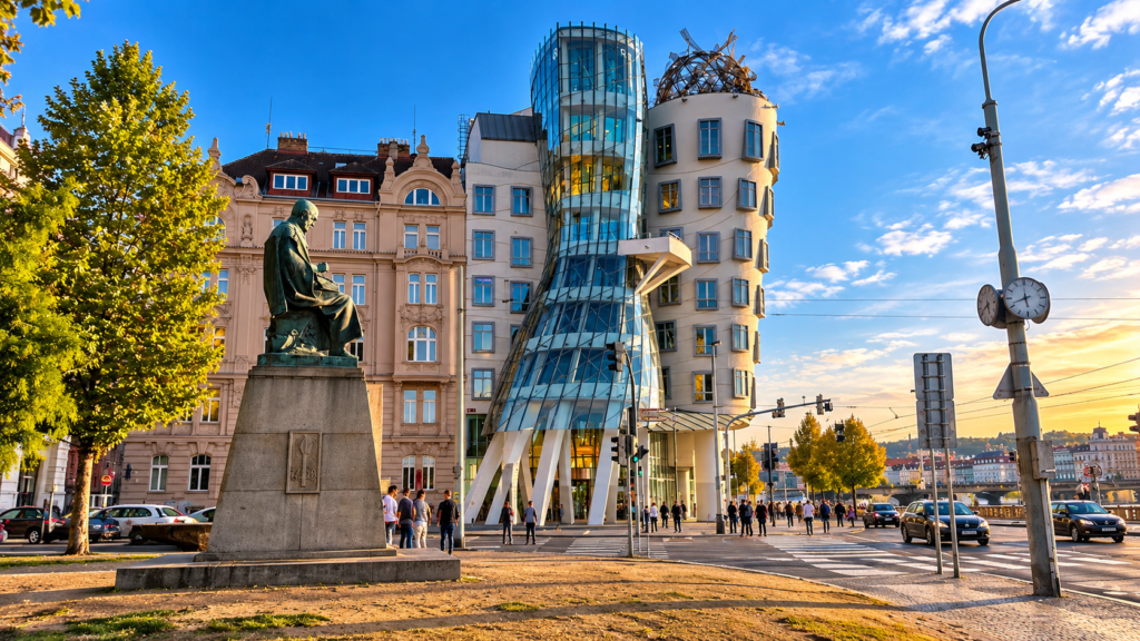 Dancing House in Prague, featuring its distinctive curved glass architecture and a statue in the foreground on a sunny day.