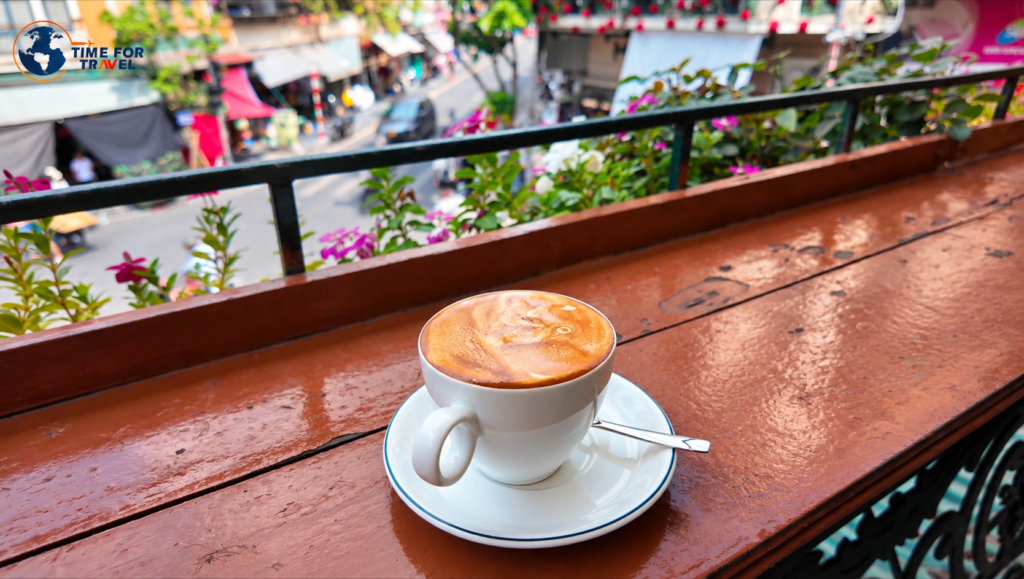 Traditional Vietnamese egg coffee in a white cup at a balcony café overlooking a street in Hanoi, Vietnam
